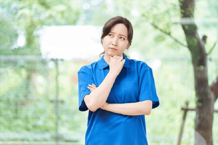 首を傾げ考える女性介護士