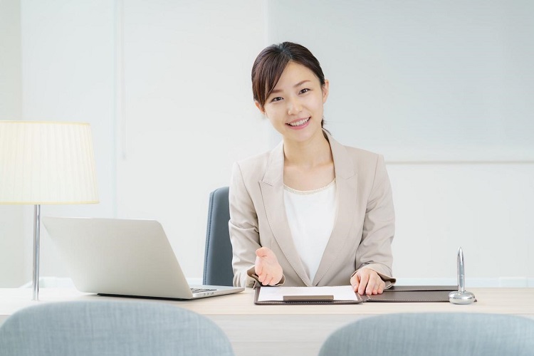 パソコンと書類を開いて説明する女性
