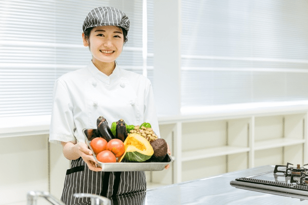 野菜を持つ調理師の女性