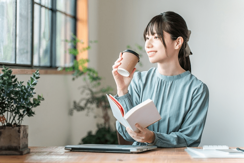 コーヒーを飲みながら勉強する女性