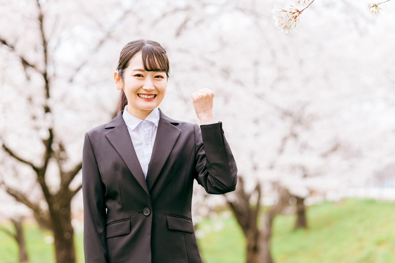 リクルートスーツの女性と桜並木