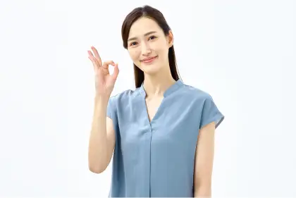青いトップスを着た笑顔の女性がOKサインを出している様子。最新キャンペーンやお得な制度を確認して満足している表情