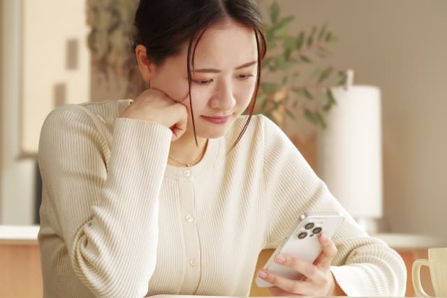 スマホを見て悩む女性