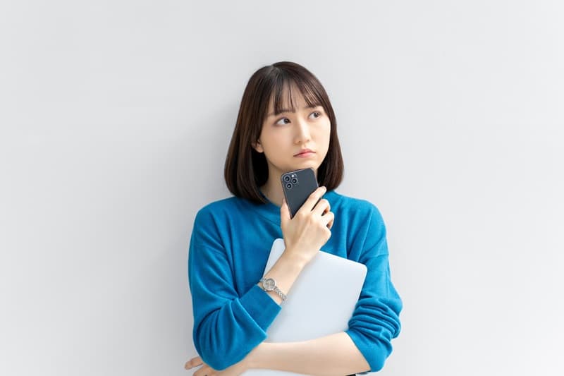 スマホを持って悩む女性