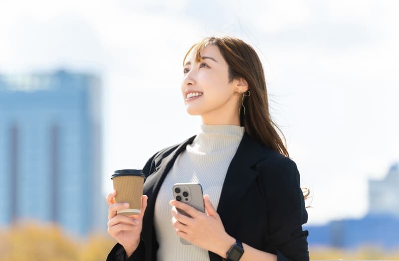 コーヒー片手に微笑む女性