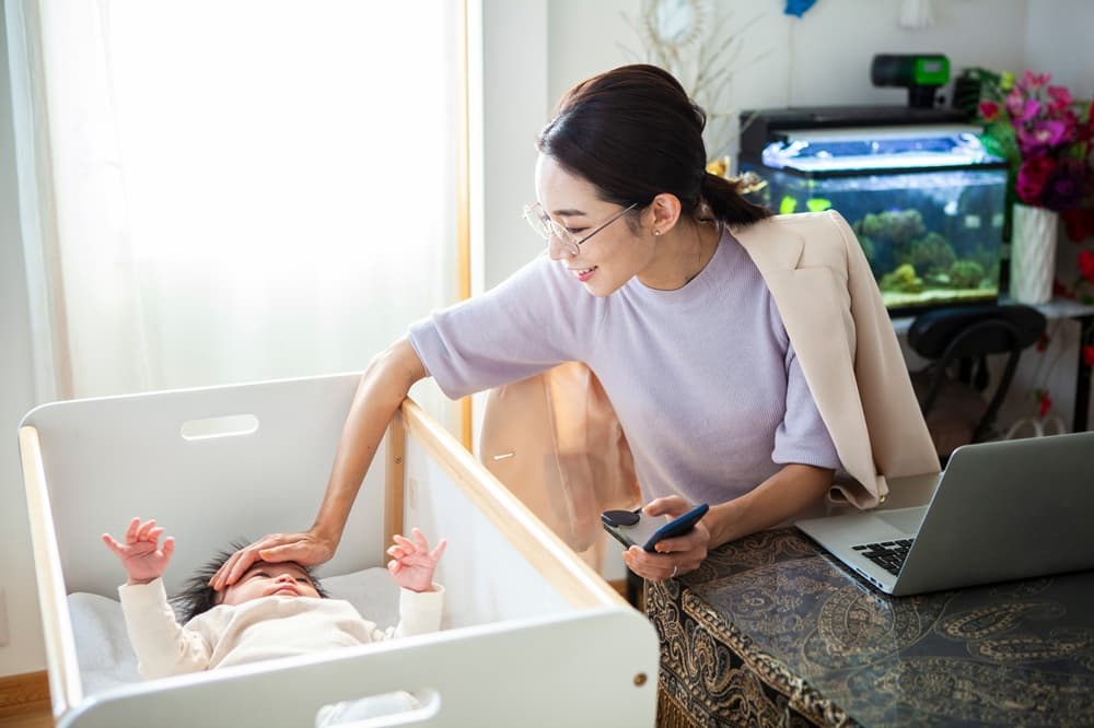 赤ちゃんを見ながら仕事する女性
